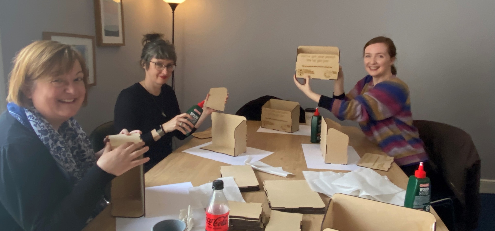Three women at a table making boxes